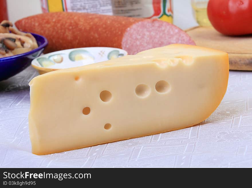 Slab of cheese with big round holes over background of other defocused ingredients for pizza. Slab of cheese with big round holes over background of other defocused ingredients for pizza