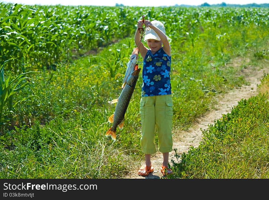 The little girl holds a catch - a big pike. The little girl holds a catch - a big pike