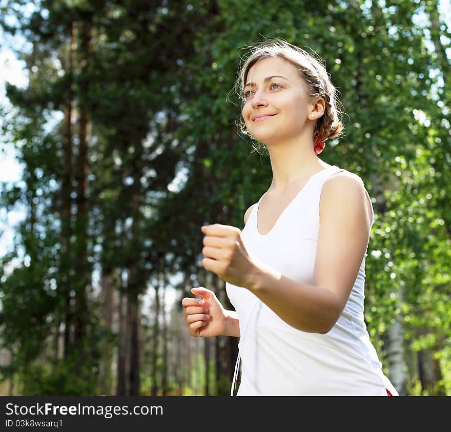 Young girl in a white shirt and red pants likes to run outdoors.