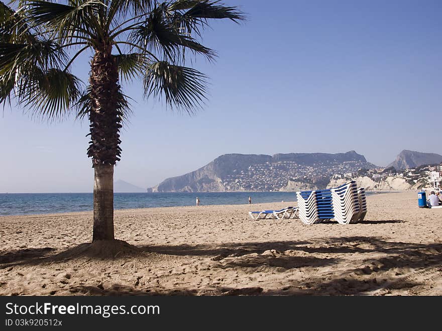 Beach with stacked sunbeds in Alicante, Spain