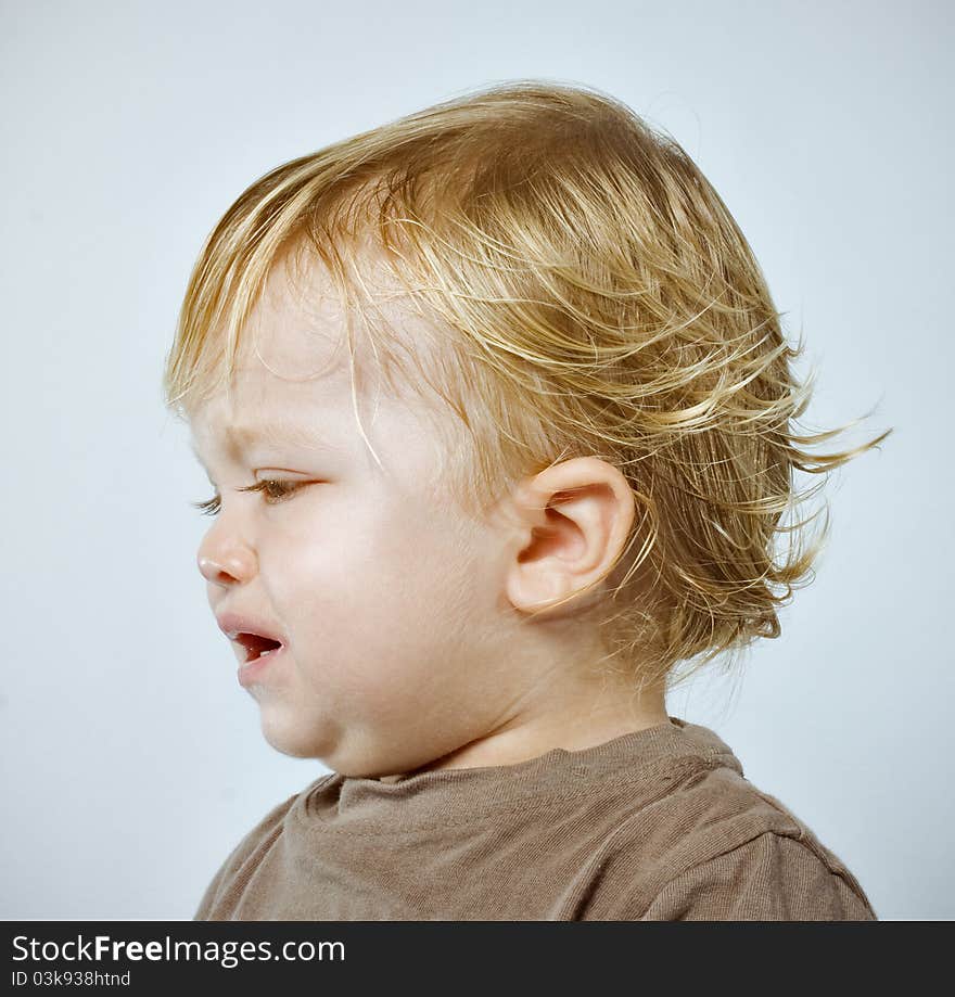 Colorful Closeup studio portrait of a crying handsome one year old blonde boy, shot against blue background. Colorful Closeup studio portrait of a crying handsome one year old blonde boy, shot against blue background.