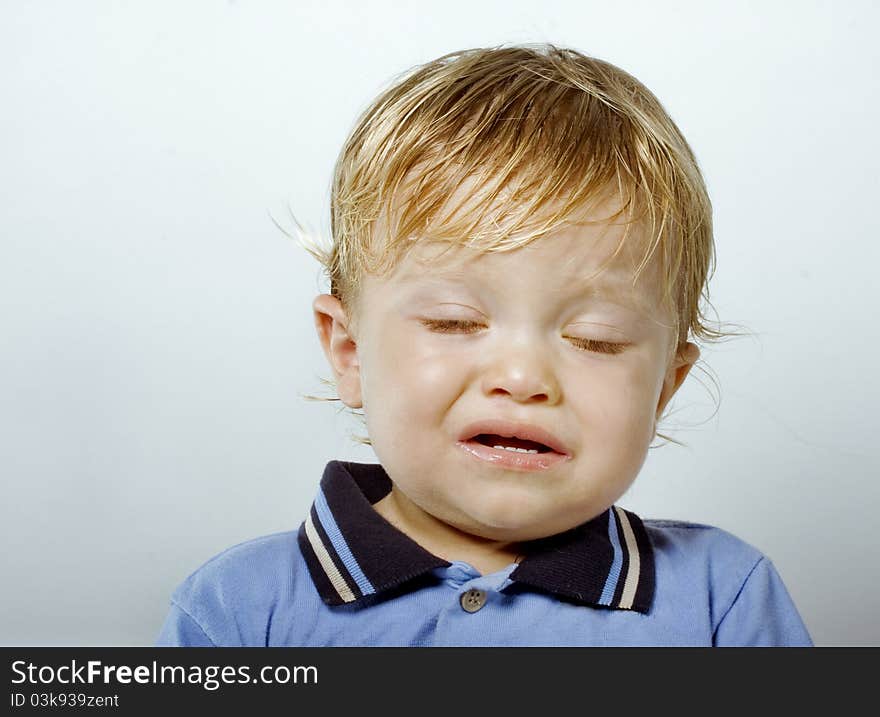 Colorful Closeup studio portrait of a crying handsome one year old blonde boy, shot against blue background. Colorful Closeup studio portrait of a crying handsome one year old blonde boy, shot against blue background.