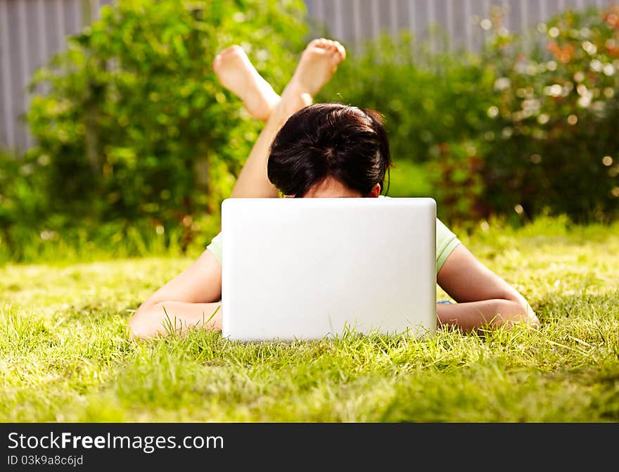 Caucasian woman is lying on the grass with laptop. Caucasian woman is lying on the grass with laptop