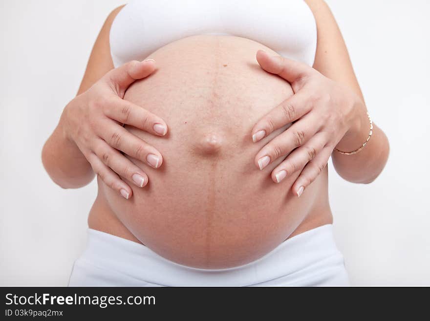 Pregnant woman hold hands on a belly isolated