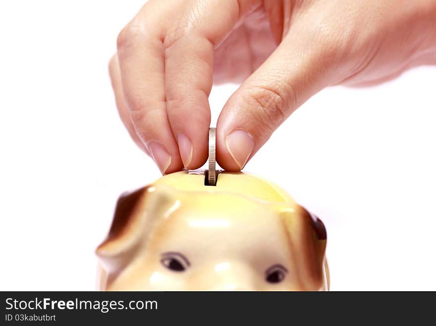 Female hand with coin and a piggy bank isolated against a white background