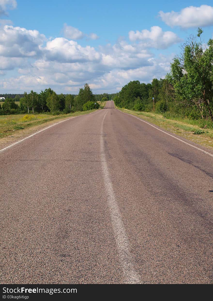 Disappearing into the distance on the road against the background of the summer landscape