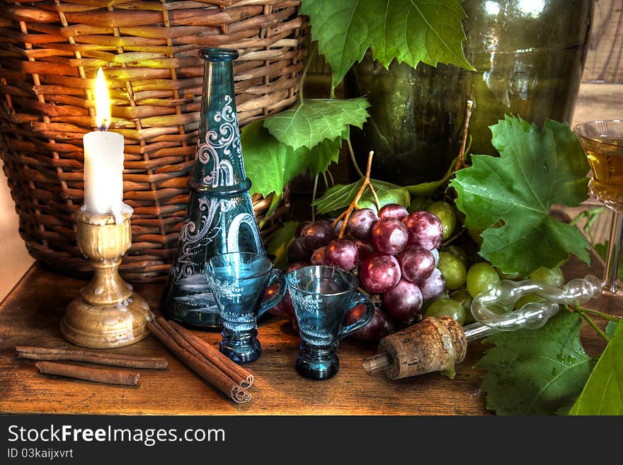 Wine,grapevine,grapes,old decanter with glasses,candlelight and wicker basket on background. Wine,grapevine,grapes,old decanter with glasses,candlelight and wicker basket on background.