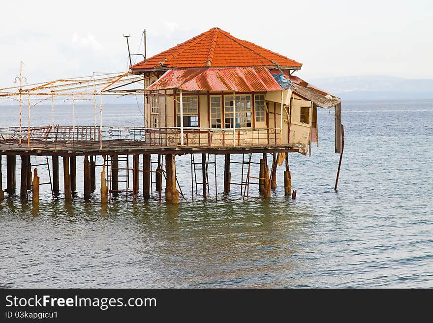 An abandoned pier with a ruined building on its edge, at Edipsos, Greece. An abandoned pier with a ruined building on its edge, at Edipsos, Greece