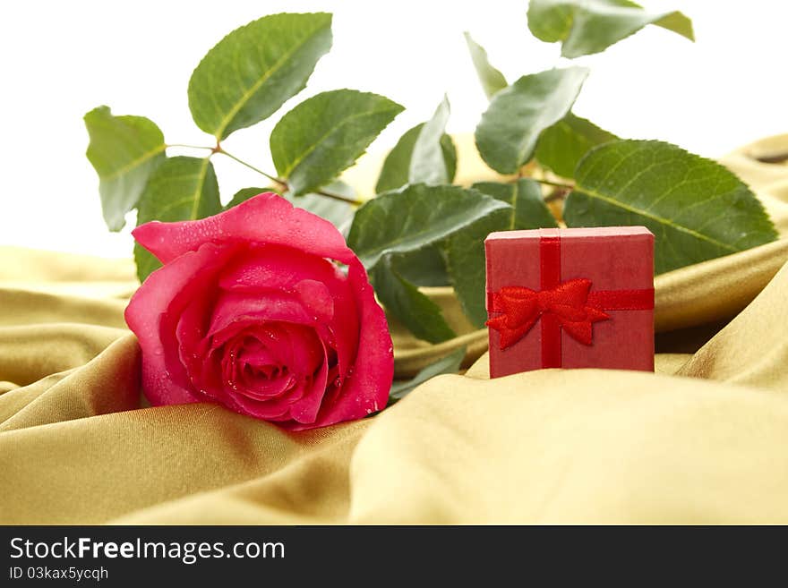 Close-up on the golden cloth red rose and a small red box. Marriage proposal. Postcard. Close-up on the golden cloth red rose and a small red box. Marriage proposal. Postcard