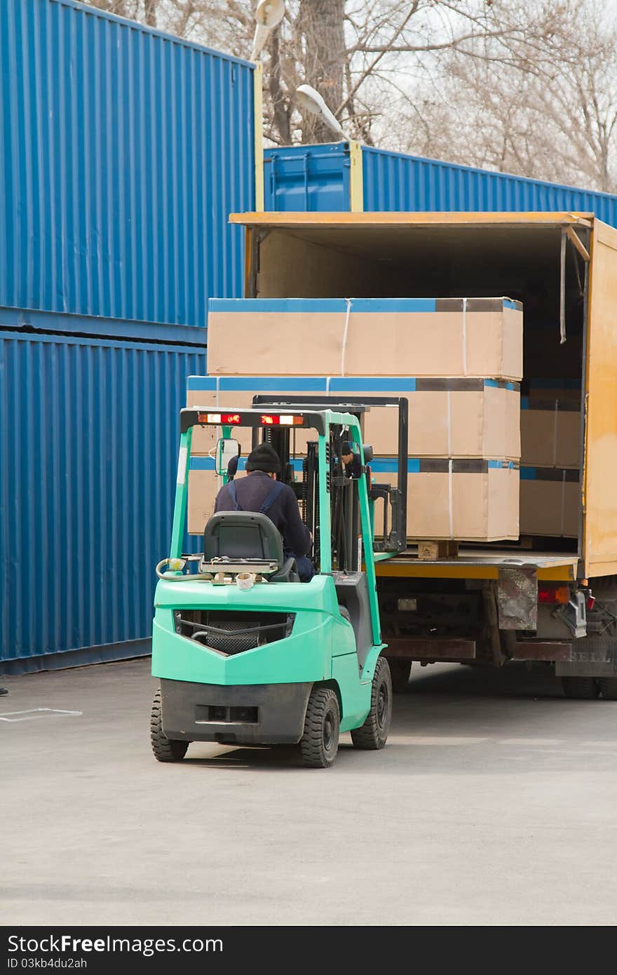 Worker in uniform loading boxes on a machine. Worker in uniform loading boxes on a machine