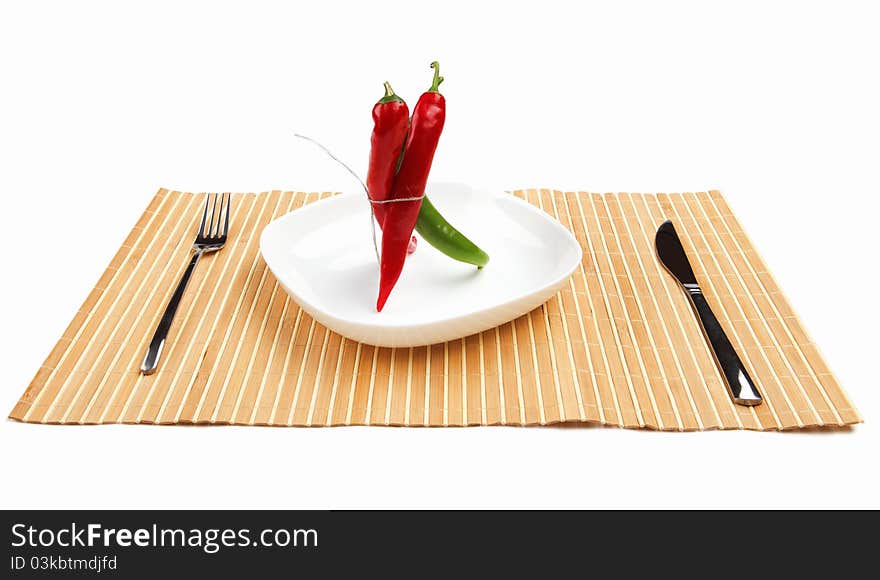 Bright red and bright green chilli pepper rolled into a bun on a white background on a white plate on the table