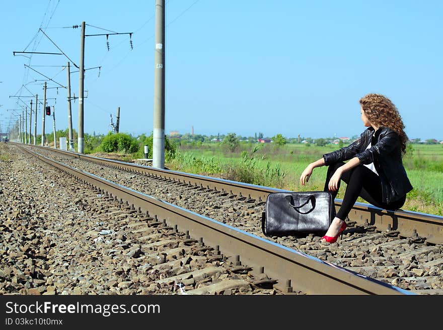 A girl sits on the rail waiting for the train. A girl sits on the rail waiting for the train