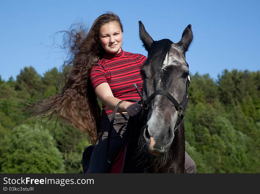 Beautiful girl with brown hair on a black horse