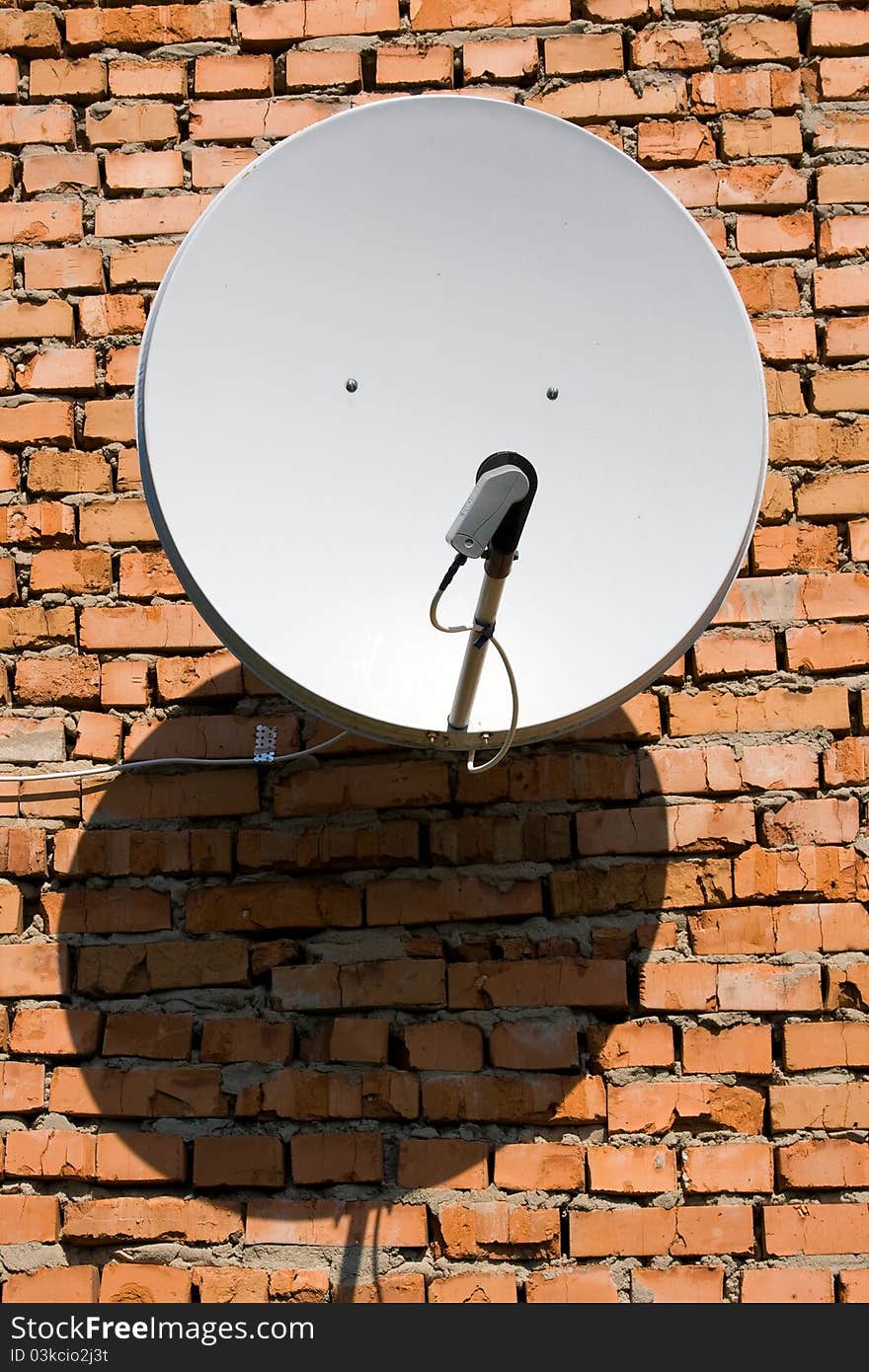 Satellite antenna on the wall of a brick house. Satellite antenna on the wall of a brick house