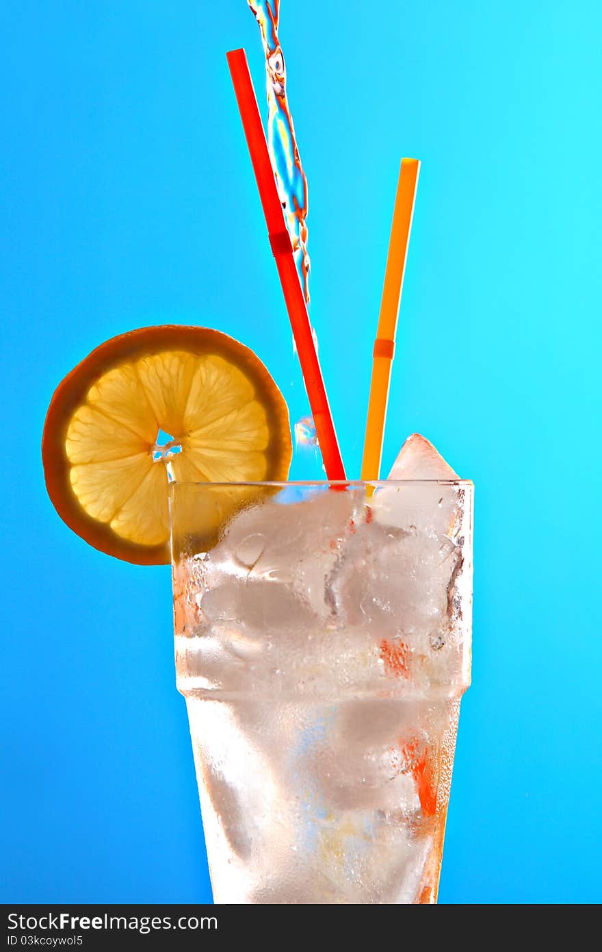 Glass of fresh ice cold water, with slice of lemon and two straws