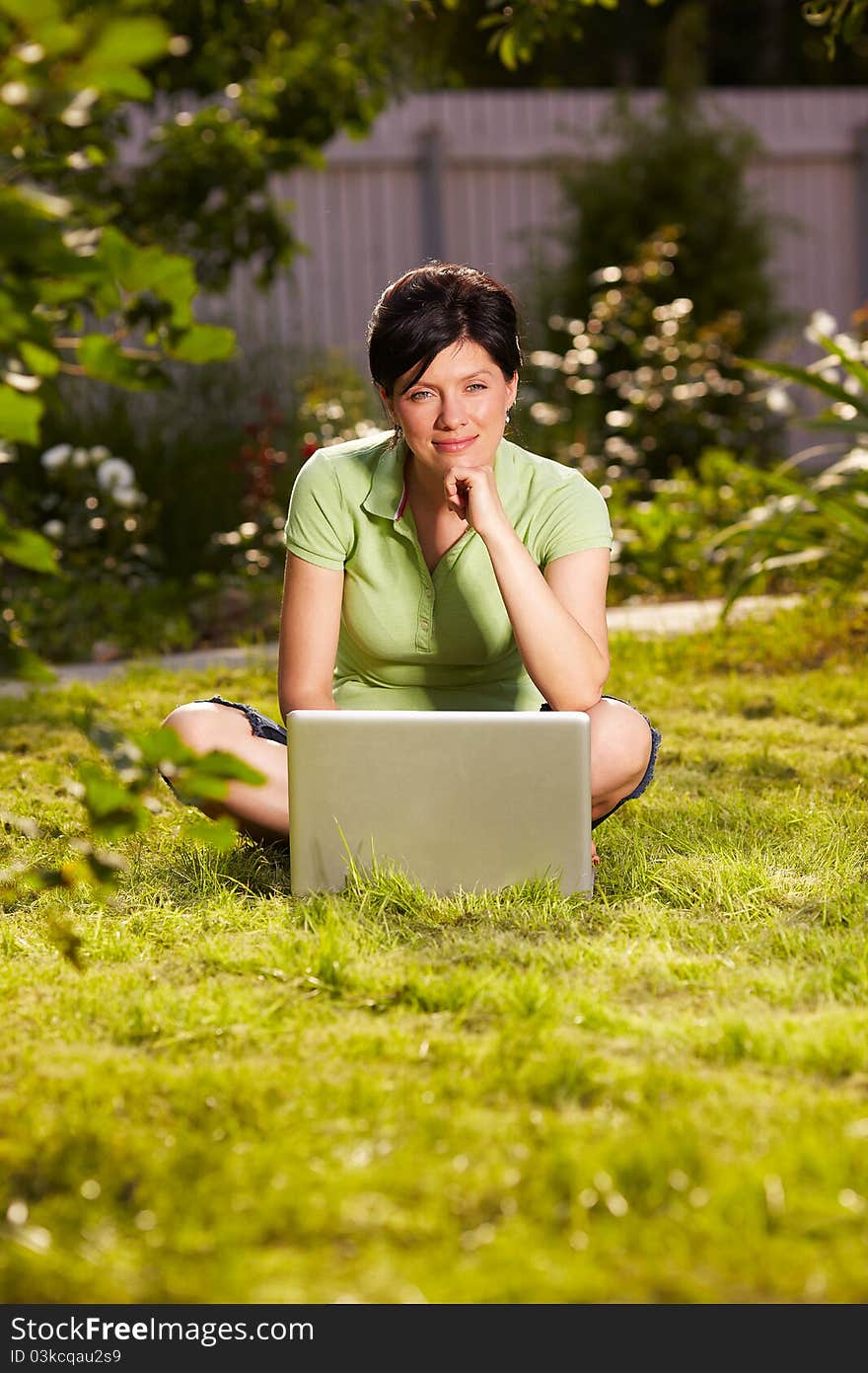 Caucasian woman is sitting on the grass with laptop. Caucasian woman is sitting on the grass with laptop