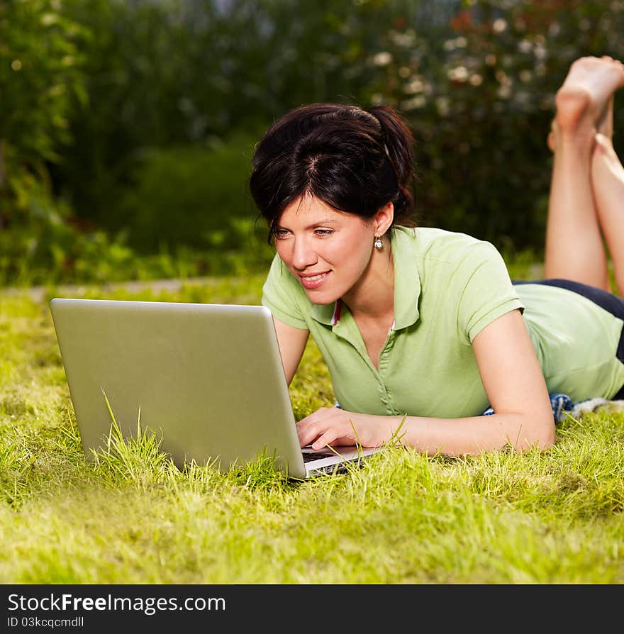 Caucasian woman is sitting on the grass with laptop. Caucasian woman is sitting on the grass with laptop