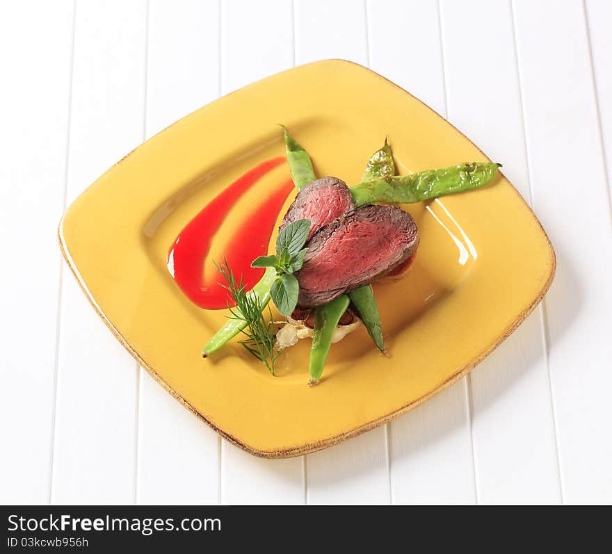 Slices of medium rare beef steak and snow peas