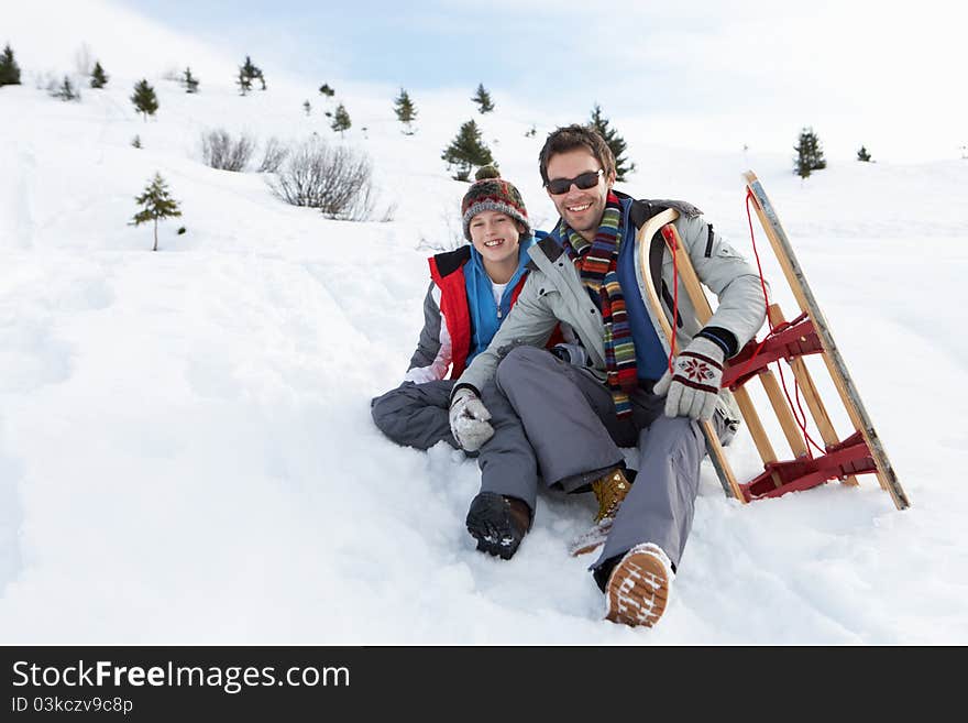 Young Father And Son In Snow With Sled