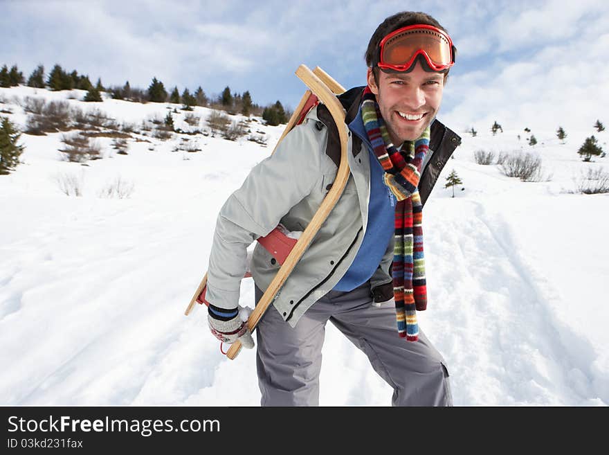 Young Man Carrying Sled In Alpine Landscape