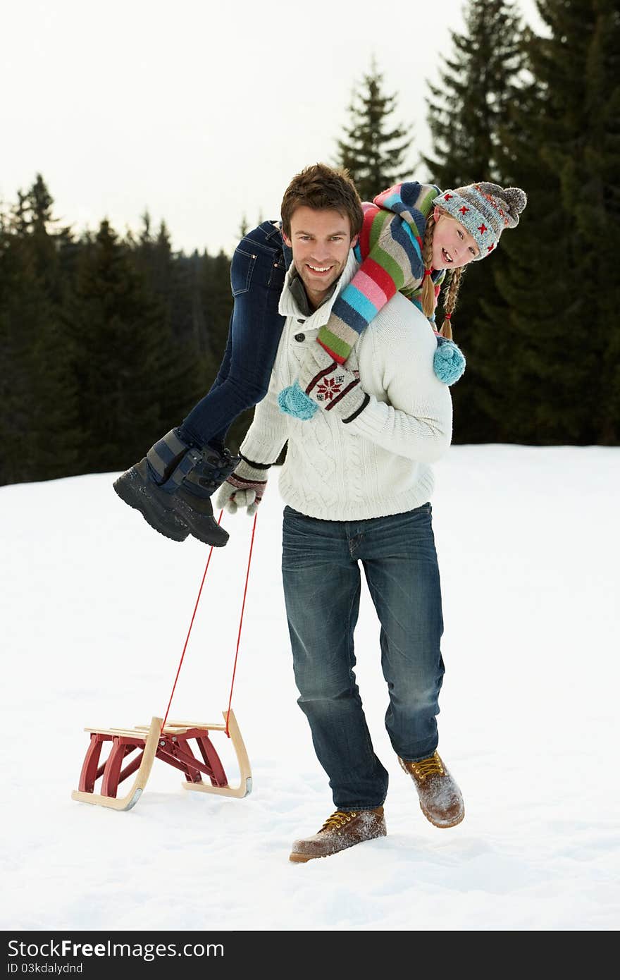 Young Father And Daughter In Snow With Sled daughter on father's back smiling