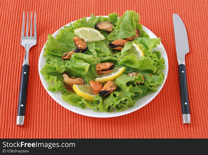 Salad with mussels and lemon on a plate