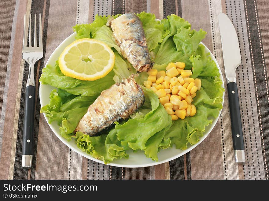 Salad with sardines and corn on a plate