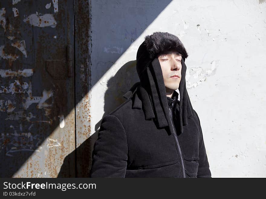 Young man closed eyes near wall