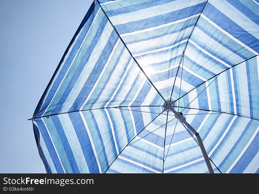 Blue Backlit Parasol Against Plain Sky