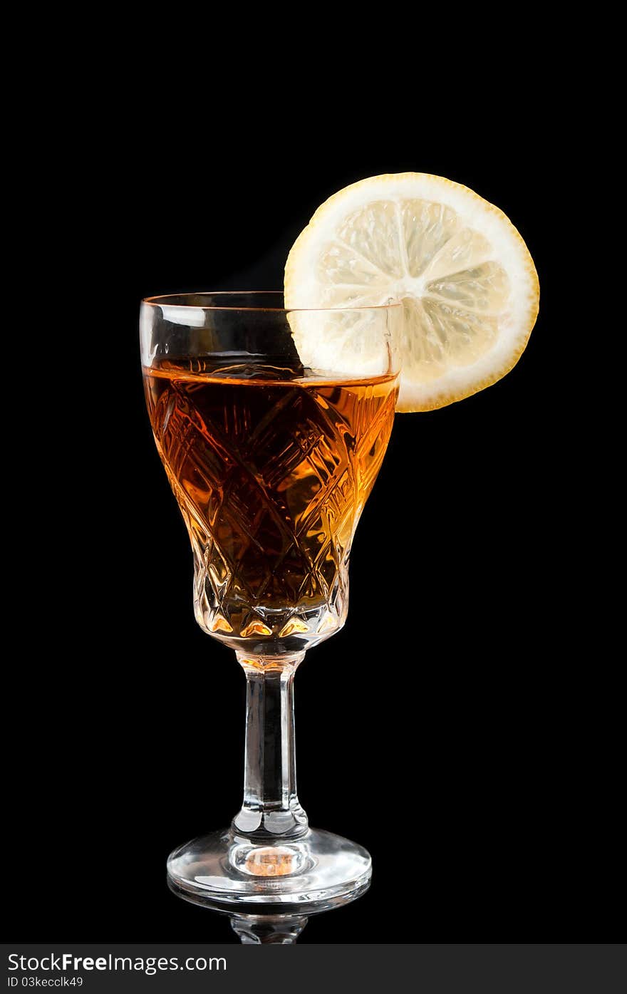 Glass of cognac with lemon isolated on a black background