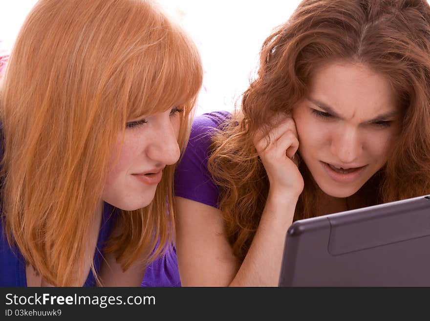 Two girls lying on the floor and looking into a laptop. Two girls lying on the floor and looking into a laptop