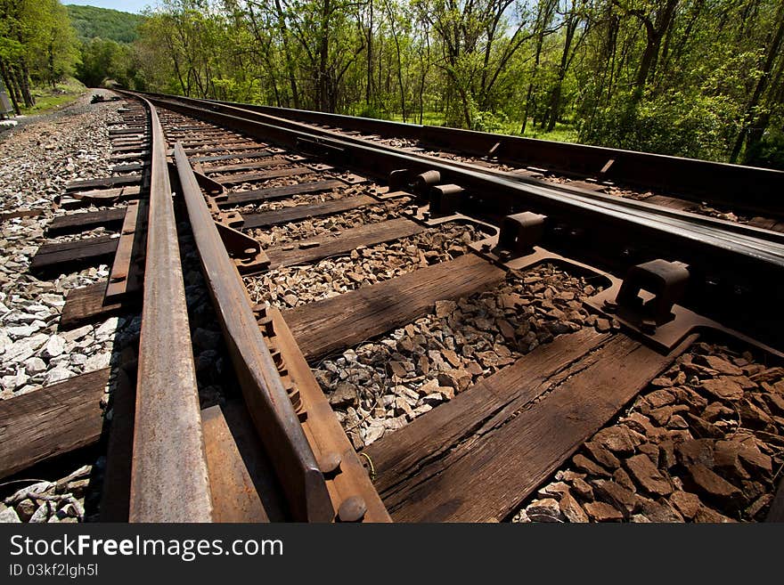 An angled view down railroad tracks in a country setting. An angled view down railroad tracks in a country setting.