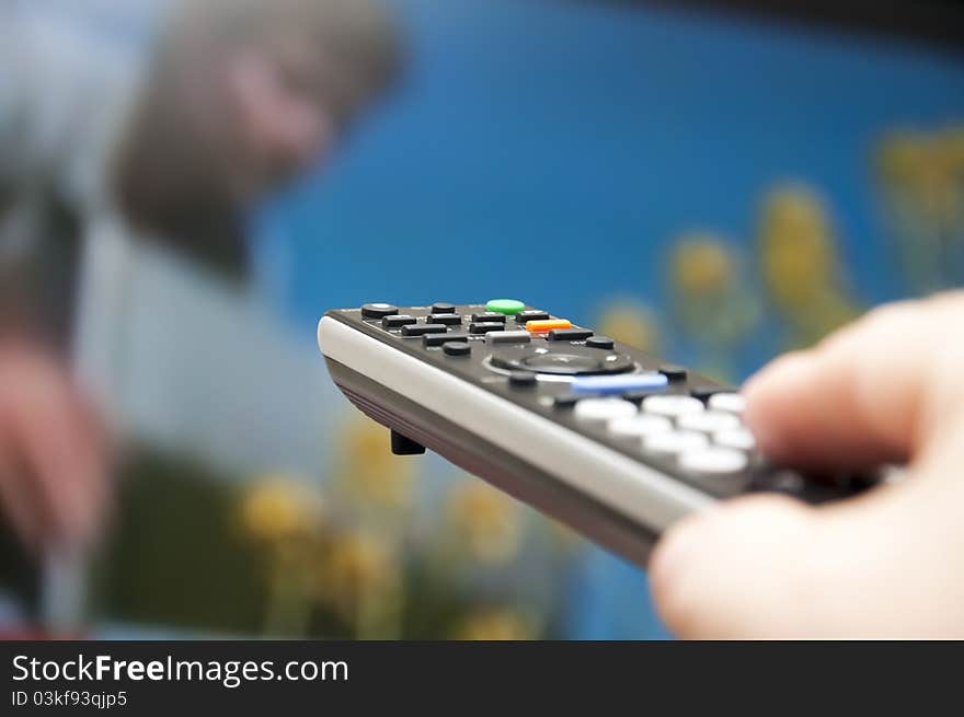 Hand holding TV remote control towards a tv screen. Hand holding TV remote control towards a tv screen.