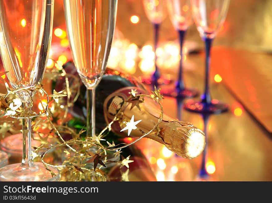 Close-up of champagne in glasses ,bottle and twinkle lights on background.