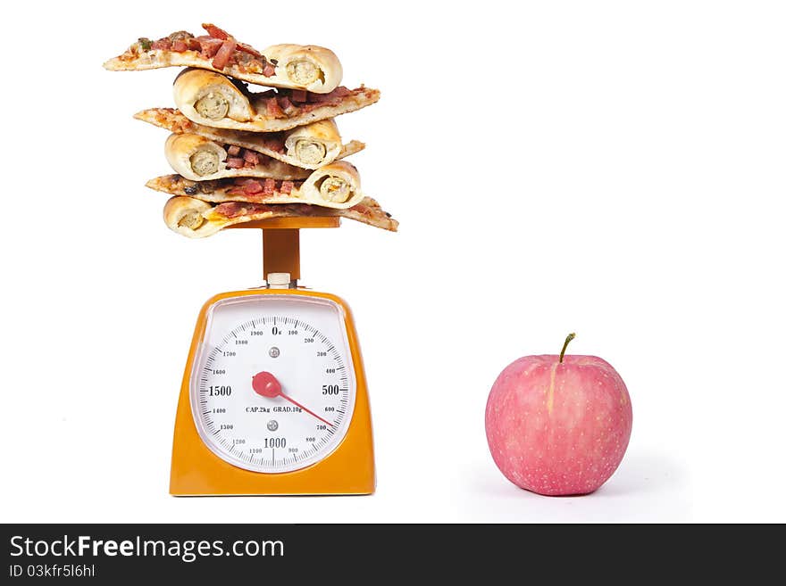 Photo of pizza slices stacked on a scale with an apple isolated over white. Photo of pizza slices stacked on a scale with an apple isolated over white