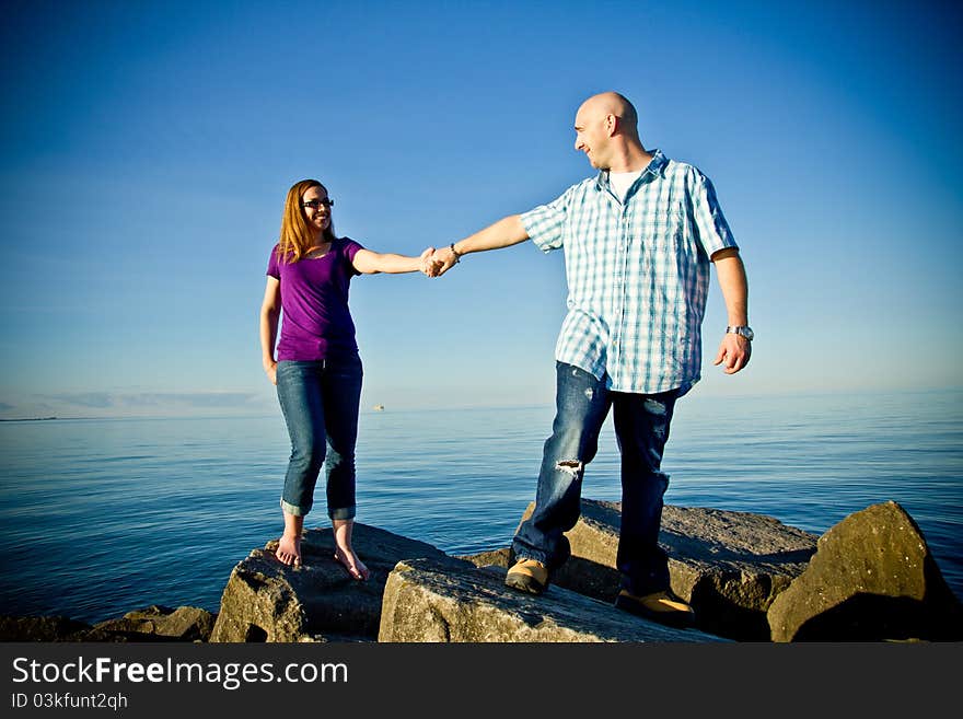 A couple standing on rocks holding hands. A couple standing on rocks holding hands.