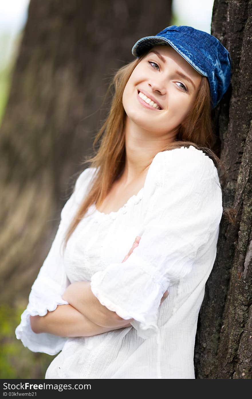 Happy young woman wearing a cap in the park on a warm summer day. Happy young woman wearing a cap in the park on a warm summer day