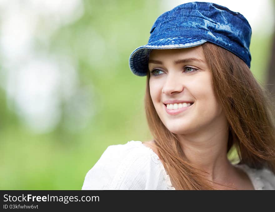 Happy young woman wearing a  cap in the park  on a warm summer day. Happy young woman wearing a  cap in the park  on a warm summer day