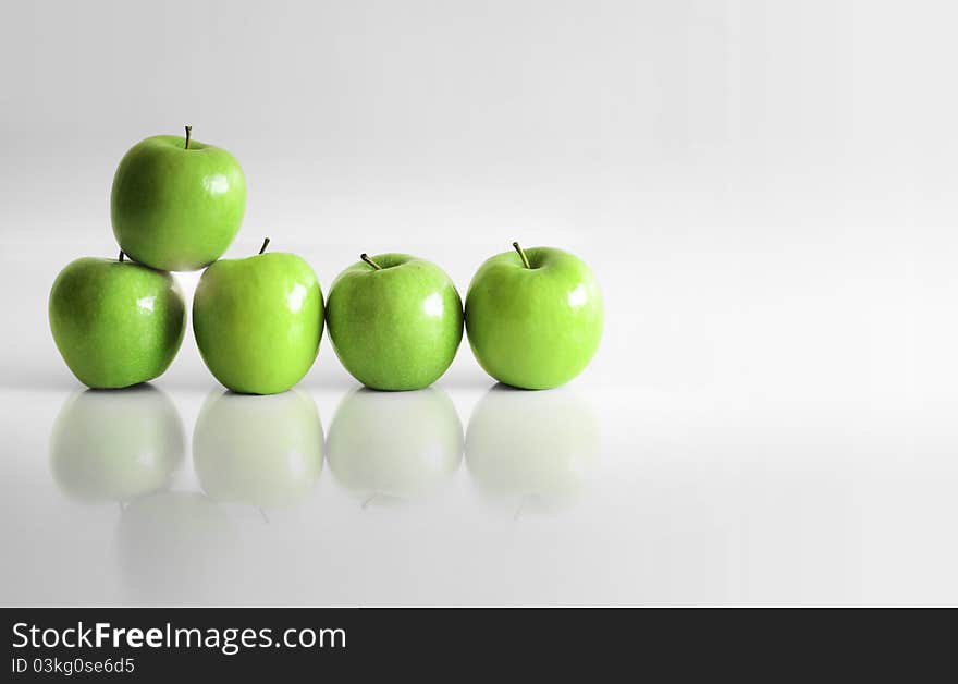 Five shiny green apples in empty white reflective space. Five shiny green apples in empty white reflective space