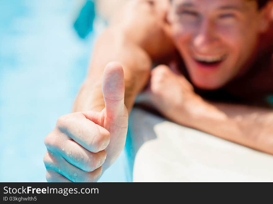 Young man showing thumb up near swimming pool. Young man showing thumb up near swimming pool