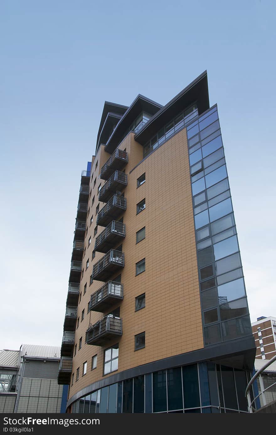 A Twenty First Century Stylish Glass and Brick Apartment Block against a blue sky. A Twenty First Century Stylish Glass and Brick Apartment Block against a blue sky