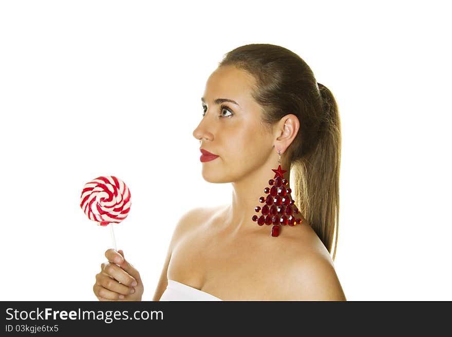 Close-up of a beautiful young woman with a lollipop and big earrings made ??of precious red stone in the form of a Christmas tree. Isolated. Close-up of a beautiful young woman with a lollipop and big earrings made ??of precious red stone in the form of a Christmas tree. Isolated