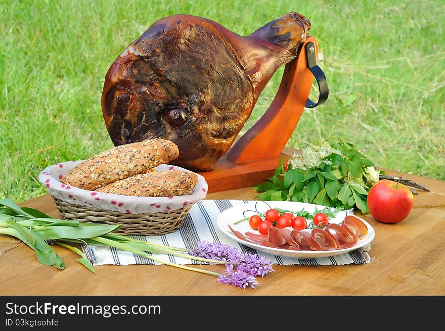 Ham on the table with tomato, bread and decoration, outdoor photo. Ham on the table with tomato, bread and decoration, outdoor photo.