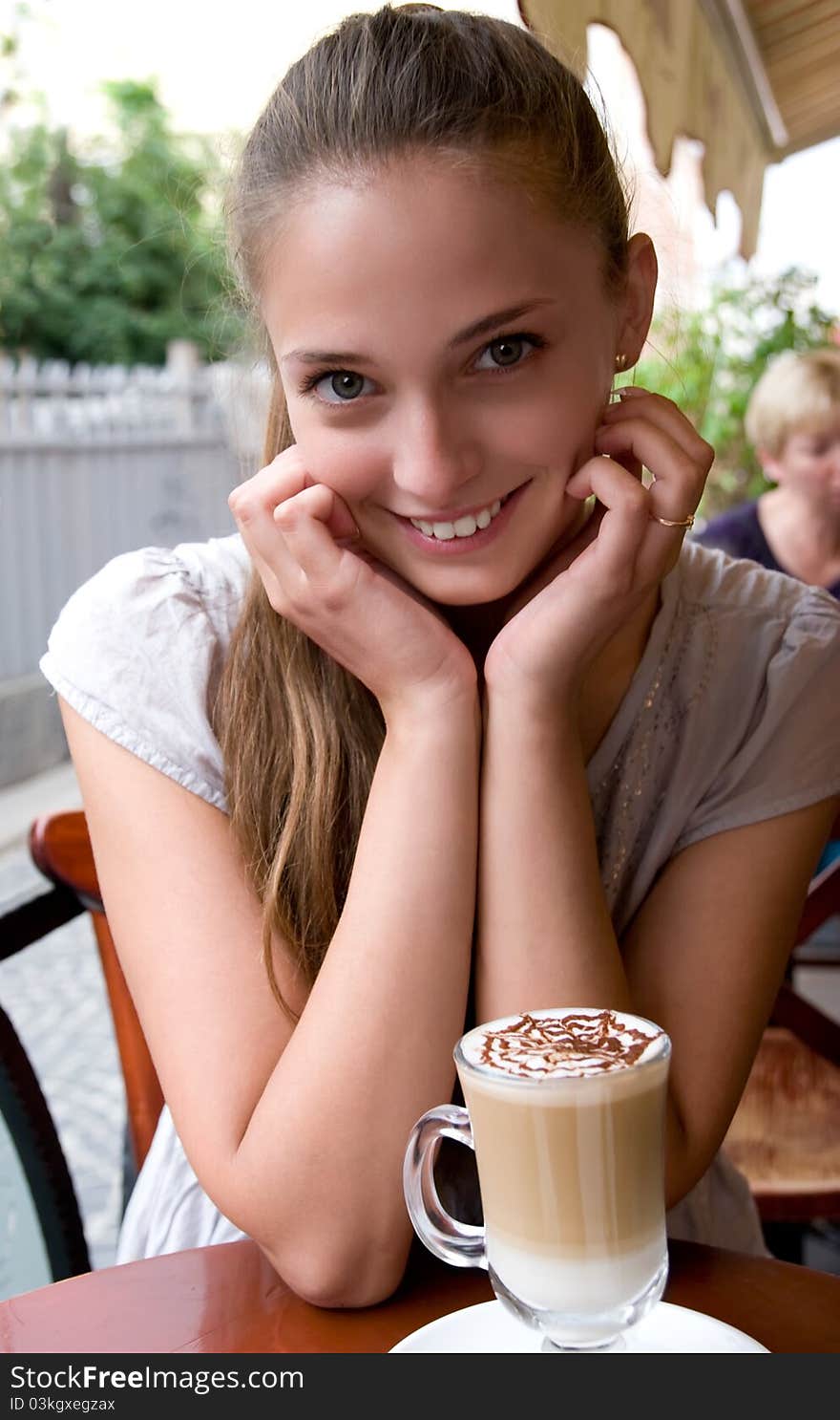 Portrait of charming smiling woman with coffee in outdoor city cafe is looking straight into camera. Portrait of charming smiling woman with coffee in outdoor city cafe is looking straight into camera