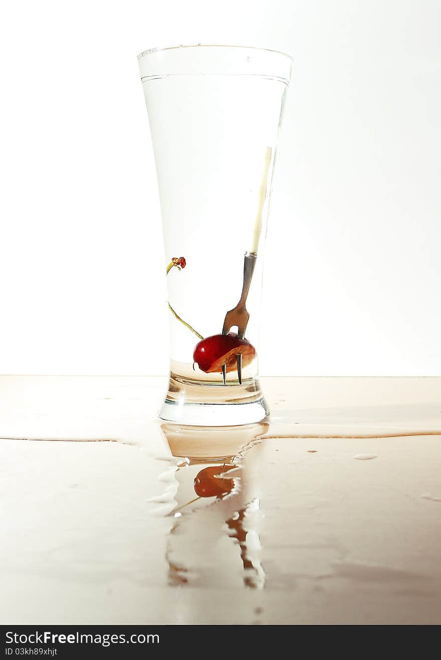 Cherry and little fork in glass full of water. Cherry and little fork in glass full of water.