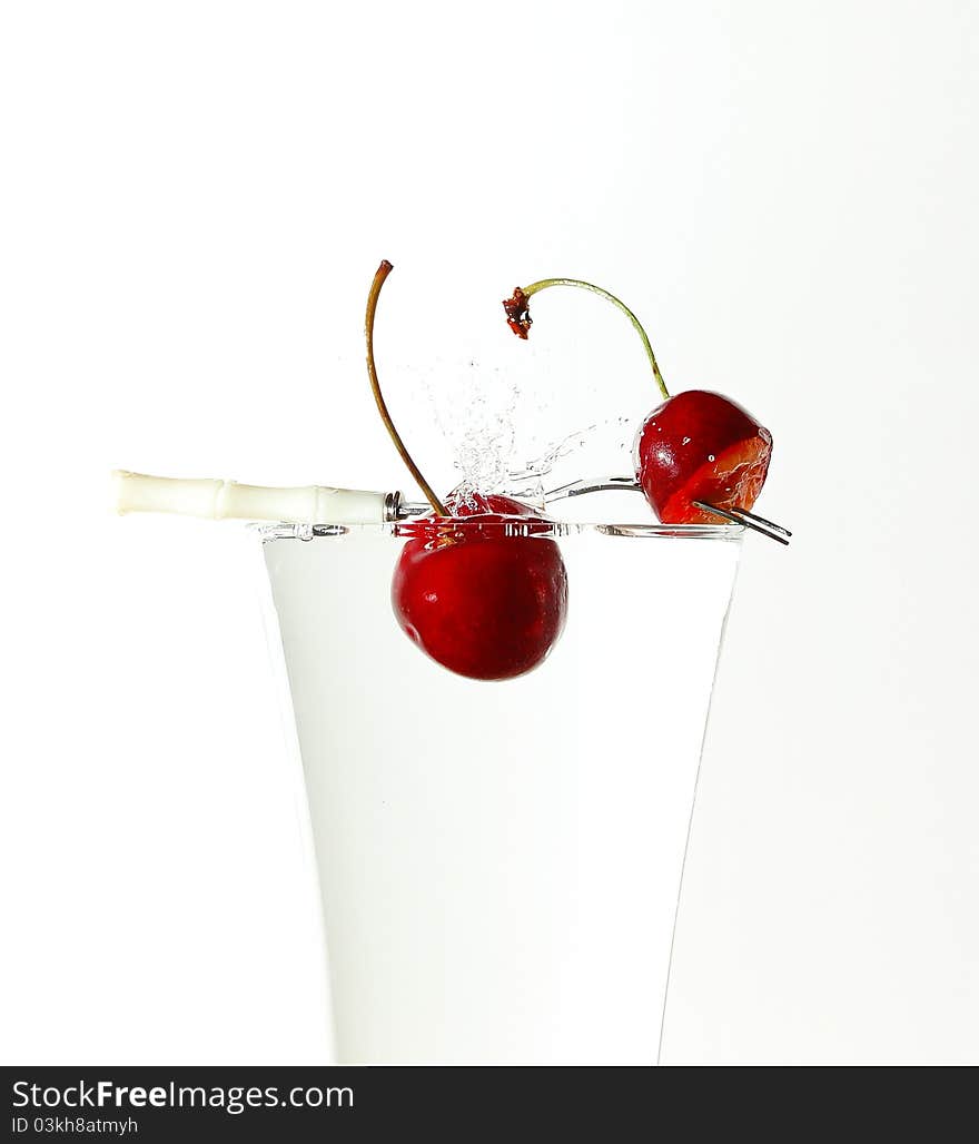 Splash with cherries in glass full of water with little fork on the top. Splash with cherries in glass full of water with little fork on the top.