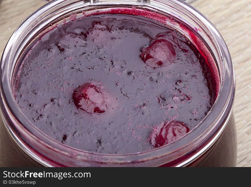 Studio-shot of homemade cherry jam in a glass jar.