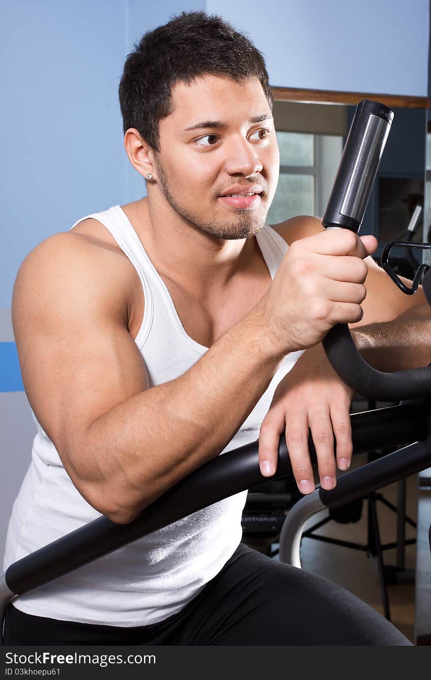 Sportsman is exercising in gym room. Sportsman is exercising in gym room