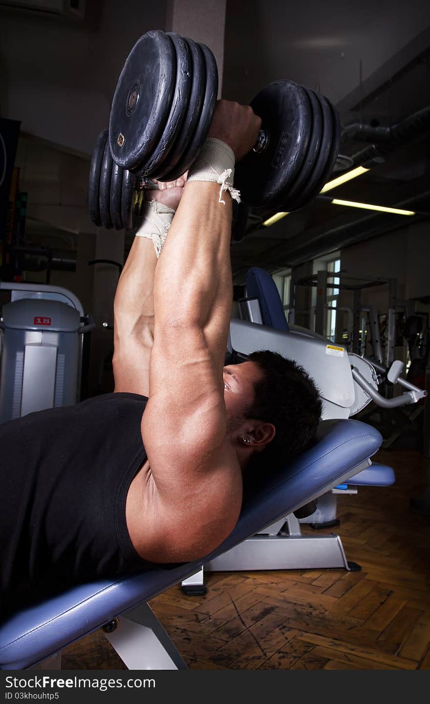 Sportsman lifting heavy dumbbells in gym. Sportsman lifting heavy dumbbells in gym