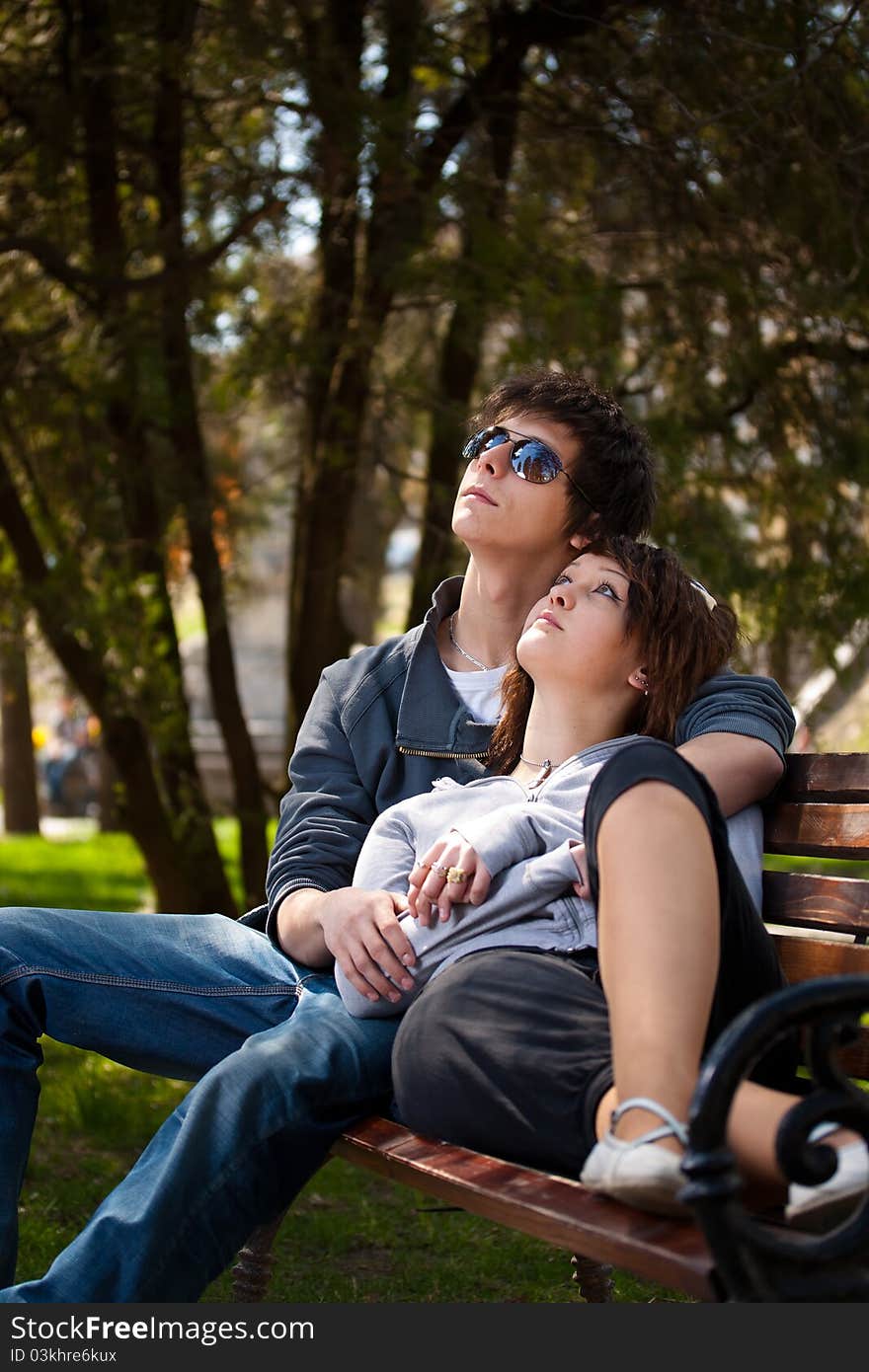 Attractive couple sitting on bench in the park and looking up. Attractive couple sitting on bench in the park and looking up